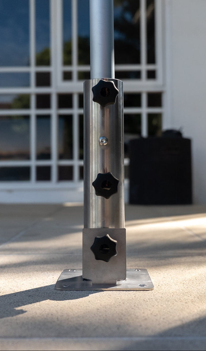 EzyHold Mount with three black knobs on a concrete surface in front of a building.